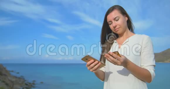 女人在度假时使用信用卡用手机上网购物蓝蓝大海背景清澈视频的预览图