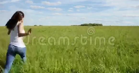 快乐美丽的女孩跑在田野的草地上视频的预览图