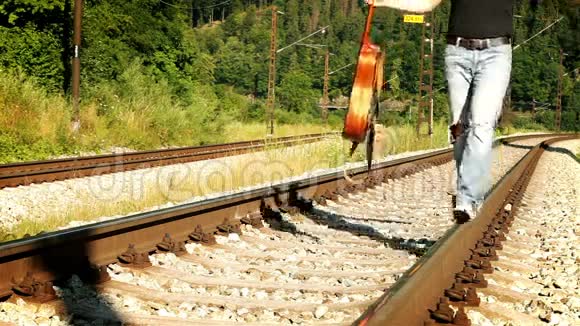 一个穿着破旧牛仔裤在铁路上行走的人的慢镜头视频的预览图