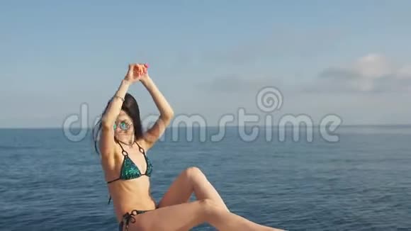 在阳光明媚的夏日穿着比基尼和太阳镜在游艇上摆姿势的年轻女孩视频的预览图