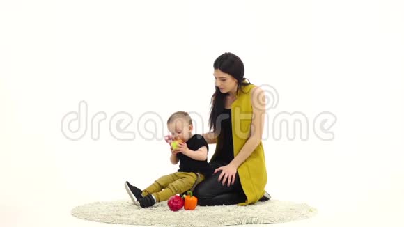 宝宝吃苹果挨着妈妈白色背景慢动作视频的预览图