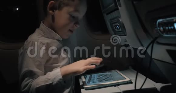 乘飞机旅行的男孩在数码平板电脑上下棋视频的预览图