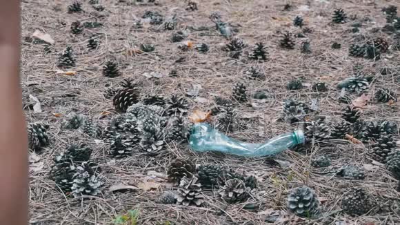 松林中的塑料瓶女人用脚咬塑料瓶慢动作视频的预览图