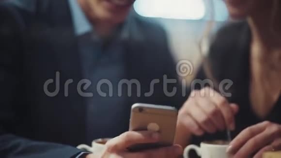 一个男人在他的智能手机上给他的女朋友看照片他们在约会时互相嘲笑和享受视频的预览图