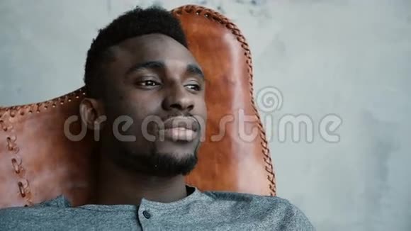 一个年轻的非洲男性坐在椅子上看着远处想着什么男人看起来很体贴视频的预览图