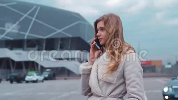 漂亮漂亮的女孩带着她的伴侣在现代商务中心前的智能手机当一辆车来的时候视频的预览图