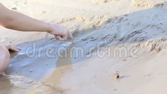 女孩在潮湿的沙子上画房子视频的预览图
