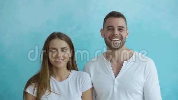 一对年轻幸福的夫妇在蓝底镜头中笑着的肖像视频的预览图