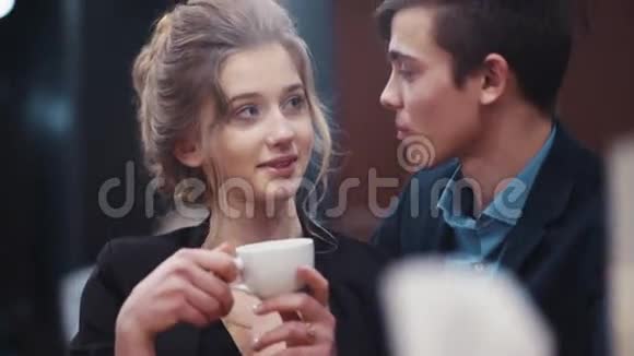 一个漂亮的女孩在约会时喝咖啡听她年轻的男朋友亲吻她视频的预览图
