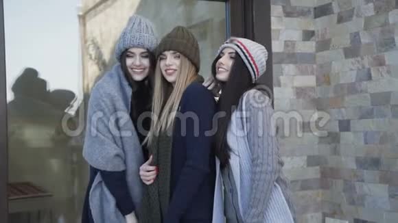 三个戴着帽子和围巾的漂亮女孩在院子里摆姿势视频的预览图