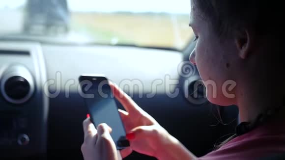 乘客女孩正坐在汽车的前排座位上在电话上写着一条信息高清1920x1080慢动作视频的预览图