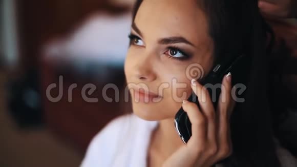 年轻的美女微笑着在房间里用手机说话视频的预览图
