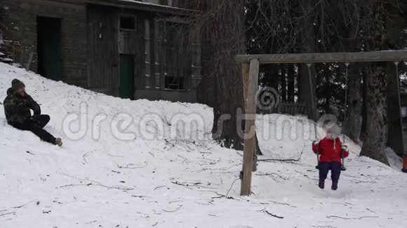 一个小女孩在秋千上荡秋千而她父亲却在她身上扔雪球4K视频的预览图