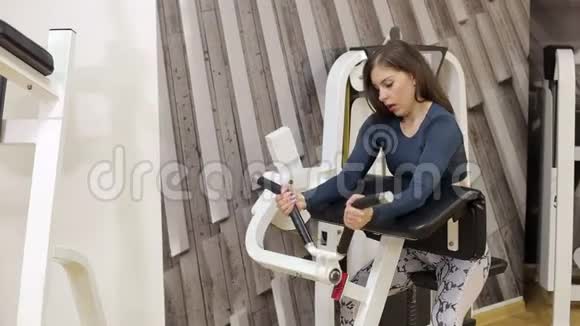 年轻的黑发在健身房锻炼手的重量视频的预览图