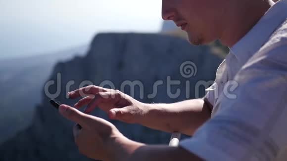 一个站在山上的人手里拿着一部手机点击一个移动屏幕高清1920x1080慢动作视频的预览图