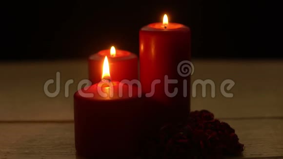 三支红烛在木桌上燃烧着浪漫的玫瑰视频的预览图