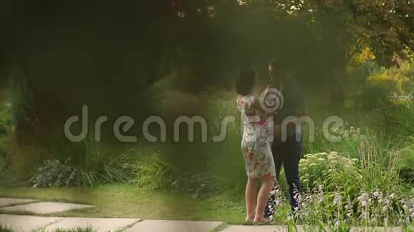 怀孕和丈夫在夏日阳光公园散步视频的预览图