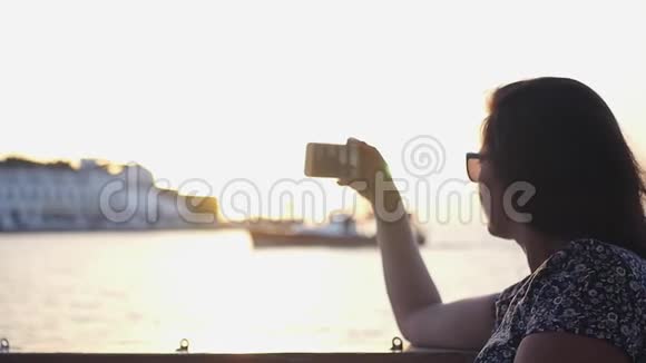 女孩在夕阳下用水在一个城市的电话上拍照高清1920x1080慢动作视频的预览图
