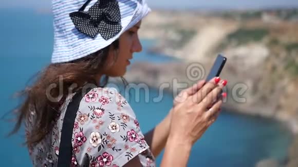 一个漂亮的女孩站在海边的斜坡上在电话里写了一条信息高清1920x1080慢动作视频的预览图