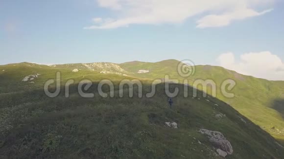 美丽的风景徒步旅行者漫步在绿色的草地上的山野景色视频的预览图