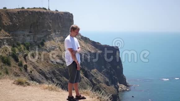 一个人站在悬崖的边缘休息和欣赏华丽的景色高清1920x1080慢动作视频的预览图
