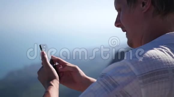 一个站在岩石上的人在电话里拍了一张照片全景高清1920x1080慢动作视频的预览图