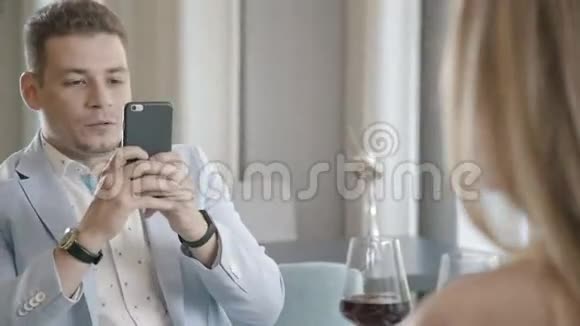 男人给他的女人拍照并在智能手机上显示照片视频的预览图