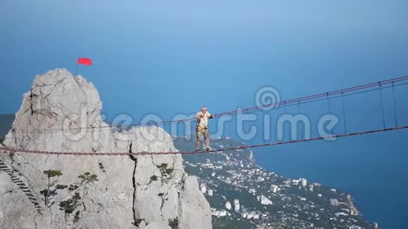 一个人在一个高海拔的悬索桥上靠着一个美丽的景色行走高清1920x1080慢动作视频的预览图
