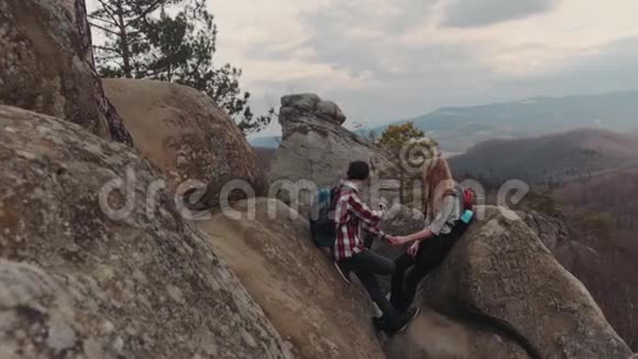 穿格子衬衫的青少年在岩石山顶上约会浪漫的时光牵手聊天视频的预览图