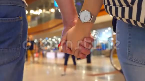 年轻夫妇牵着手在机场候机楼散步男人和女人抱着胳膊踩着脚视频的预览图