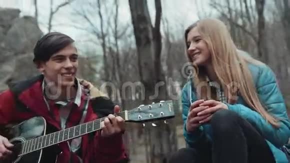 年轻的音乐家们在一起玩得很开心他们用吉他演奏一首歌给他心爱的女朋友女朋友端着一杯茶他们视频的预览图