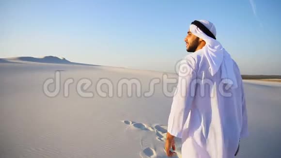 欢乐的阿拉伯谢赫人走在沙漠的顶部在晴朗的夏日户外微笑视频的预览图