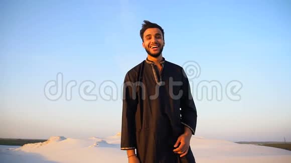 一幅快乐的阿拉伯男人的画像他微笑着看着镜头站在沙漠中露天视频的预览图