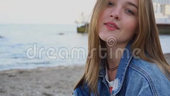 慢动作特写的可爱女孩谁微笑和看相机坐在海滩上温暖的夏天晚上视频的预览图