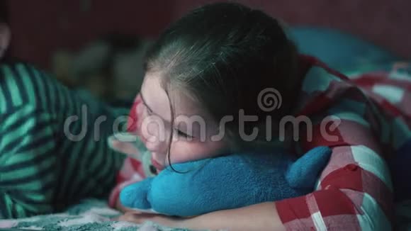 多民族家庭姐姐和哥哥躺在床上看着笔记本电脑平板电脑特写的电影视频的预览图