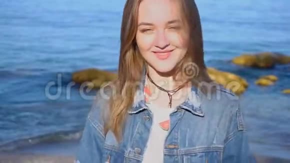 在温暖的夏季天气里可爱的女孩因阳光明媚而快乐在蔚蓝的海洋海岸上摆姿势视频的预览图