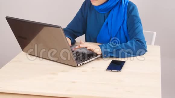 年轻的穆斯林妇女坐在办公室用笔记本电脑工作视频的预览图