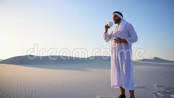 在大沙漠中的阿拉伯酋长盖伊在蓝天的映衬下喝杯咖啡的美好开始视频的预览图