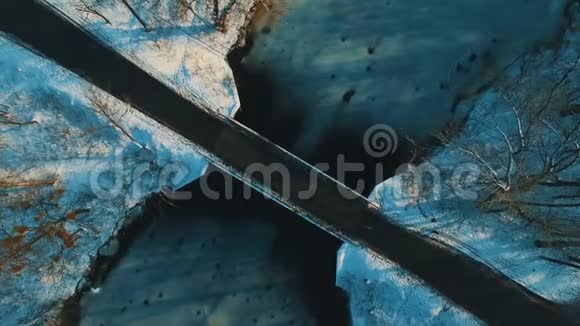 冬季森林无人机拍摄的穿越冰冻湖的桥上鸟瞰图视频的预览图