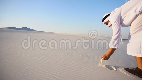 穆斯林人阿拉伯阿联酋谢赫在晴朗的夏日沿着风缓慢地发展沙子站在沙漠中间视频的预览图