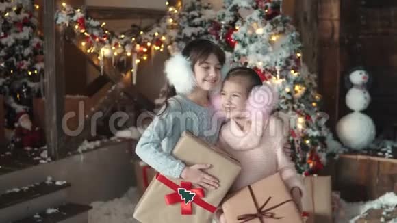 圣诞节或新年两个小女孩拿着包装精美的礼物的肖像儿童收到礼物视频的预览图
