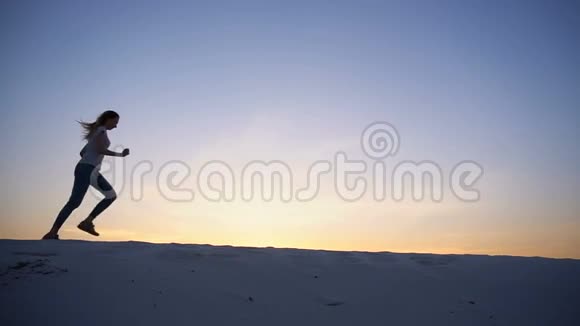 两个相爱的心男人和女孩正在享受乐趣并在夏天的夜晚在沙漠的山丘上奔跑开放视频的预览图