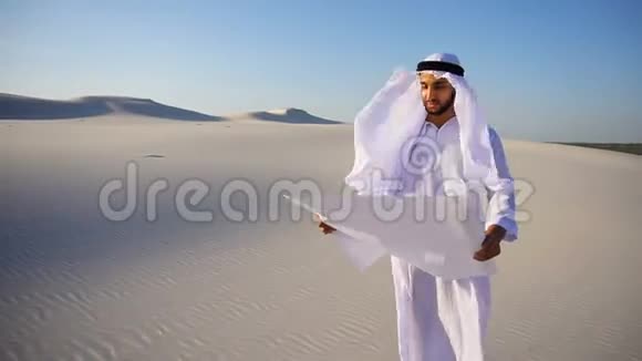 严肃的年轻阿拉伯阿联酋谢赫商人考虑建造计划在炎热的夏日站在广阔的沙漠中视频的预览图