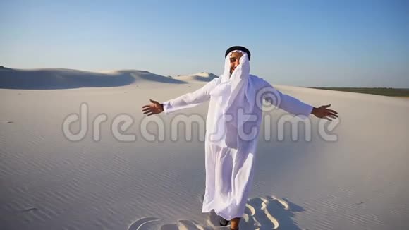 慢动作的肖像自信的男性阿拉伯阿联酋谢赫在坎杜拉在白色沙漠中的晴天视频的预览图