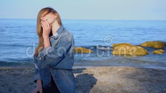 可爱的女孩去了黑海海岸微笑着看着远方在凉爽的夏日站在海滩上视频的预览图