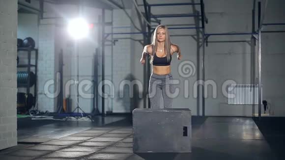 年轻强壮的金发女人穿着运动服在健身房做一套盒子跳跃女孩跳进去视频的预览图