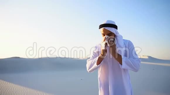 在炎热的夜晚阿拉伯男孩站在沙质沙漠中感到寒冷而不愉快视频的预览图