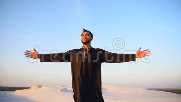 阿拉伯酋长国男性慢动作的快乐肖像他微笑着在生活中欢欣鼓舞站在广阔的沙漠中视频的预览图