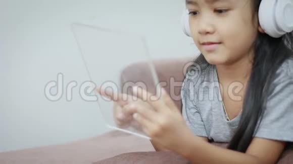 亚洲小女孩使用白色无线耳机和透明垫的未来技术移动应用概念视频的预览图
