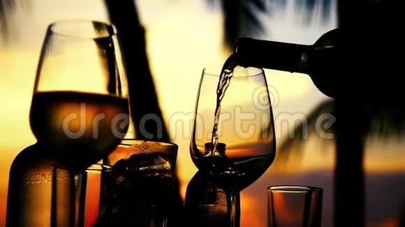 在令人惊叹的日落时分在海滩餐厅的海景中缓慢地在玻璃中倒入白酒1920x1080视频的预览图